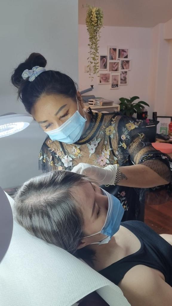 woman piercing the ear of a female client